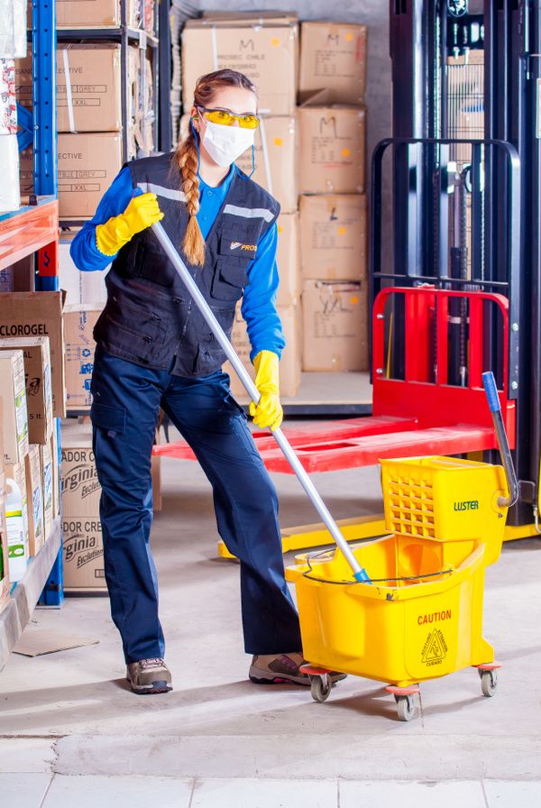 Janitor mopping a large floor with a bucket