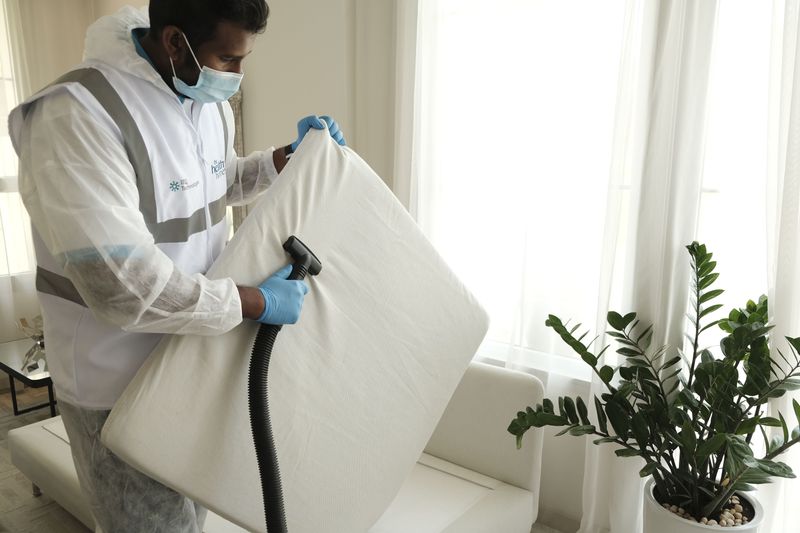 Technician deep cleaning a mattress with specialist equipment